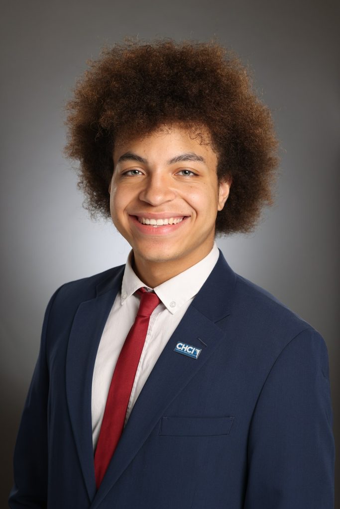 Professional image of Michigan State University student Roberto (Marcos) Garcia smiling in a navy blazer, white collared shirt, and red tie. The background is a gray gradient.