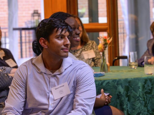 Aaron Philip sits at a table at an Honors College scholarship recipient and donor dinner on Michigan State University’s campus in Cowles House.