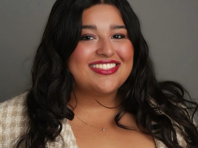 Michigan State University student and Voyager Scholarship recipient Anabelle Sanchez smiling in a plaid white and tan blazer, wearing a red CHCI ALUMNI pin.